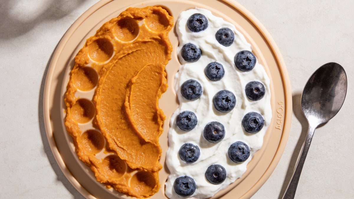 Silicone lick mat spread with pumpkin and yogurt with blueberries on a kitchen counter